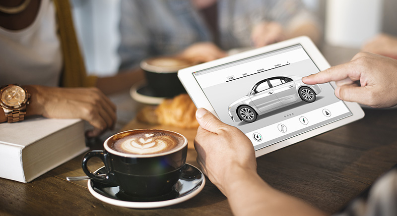 Customer using a tablet to explore and customize a Buick SUV while discussing options at a café, highlighting convenient financing and digital shopping experience.