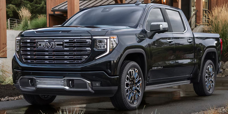 Black GMC Sierra 1500 Denali pickup truck parked in front of a modern home.