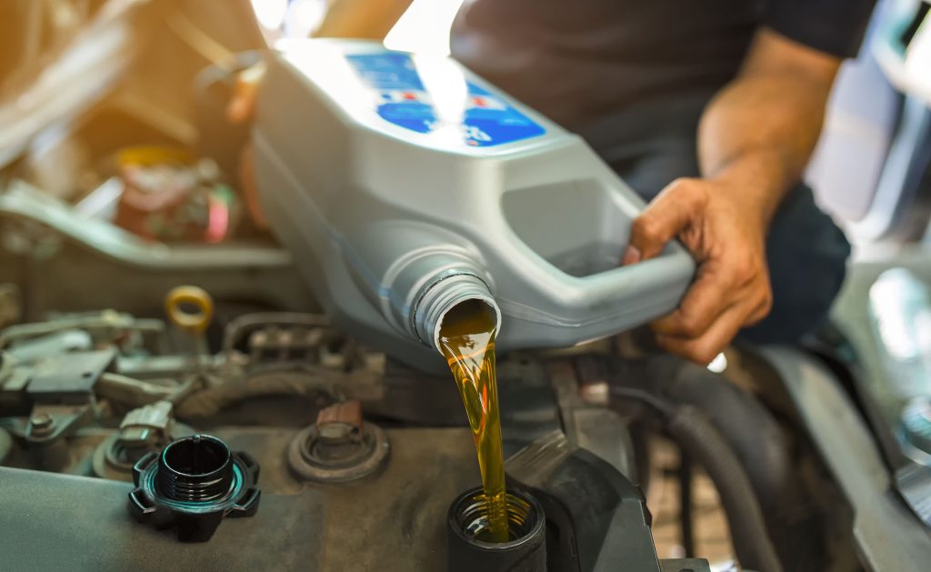 Person pouring oil into a car engine during oil change.